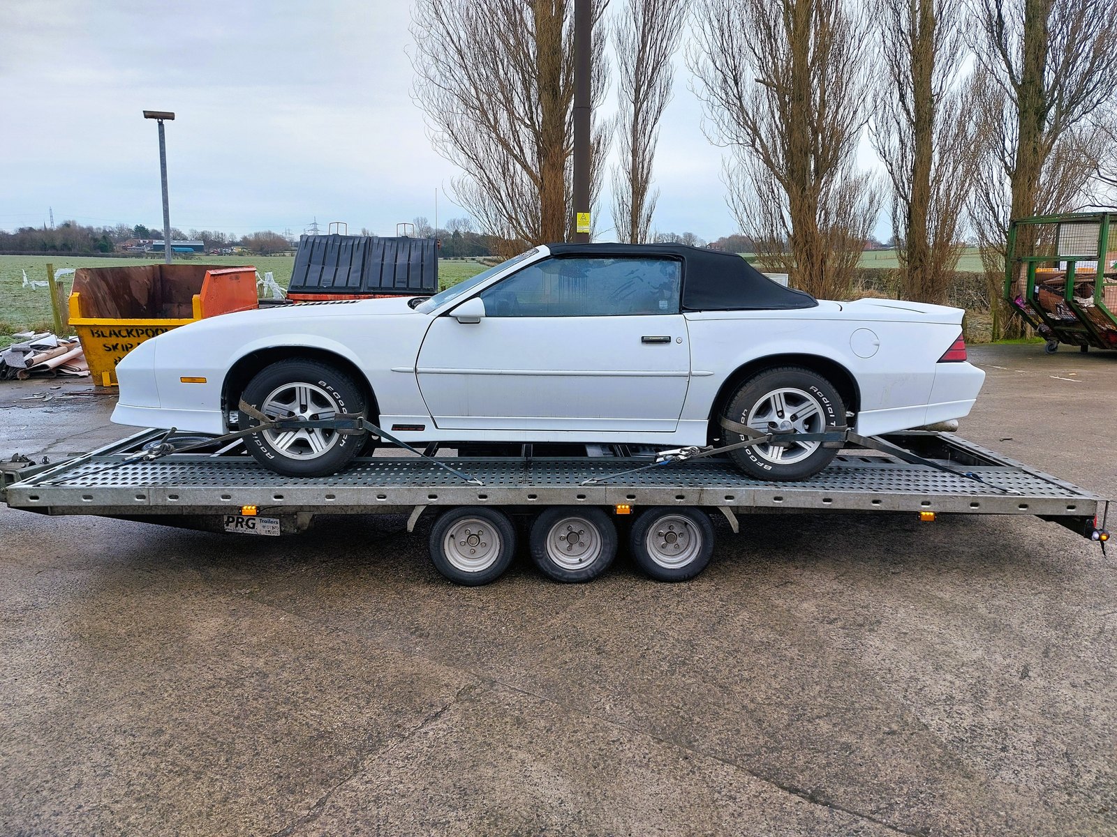 White Chevrolet Camaro convertible strapped down on the WS Logistics open transporter