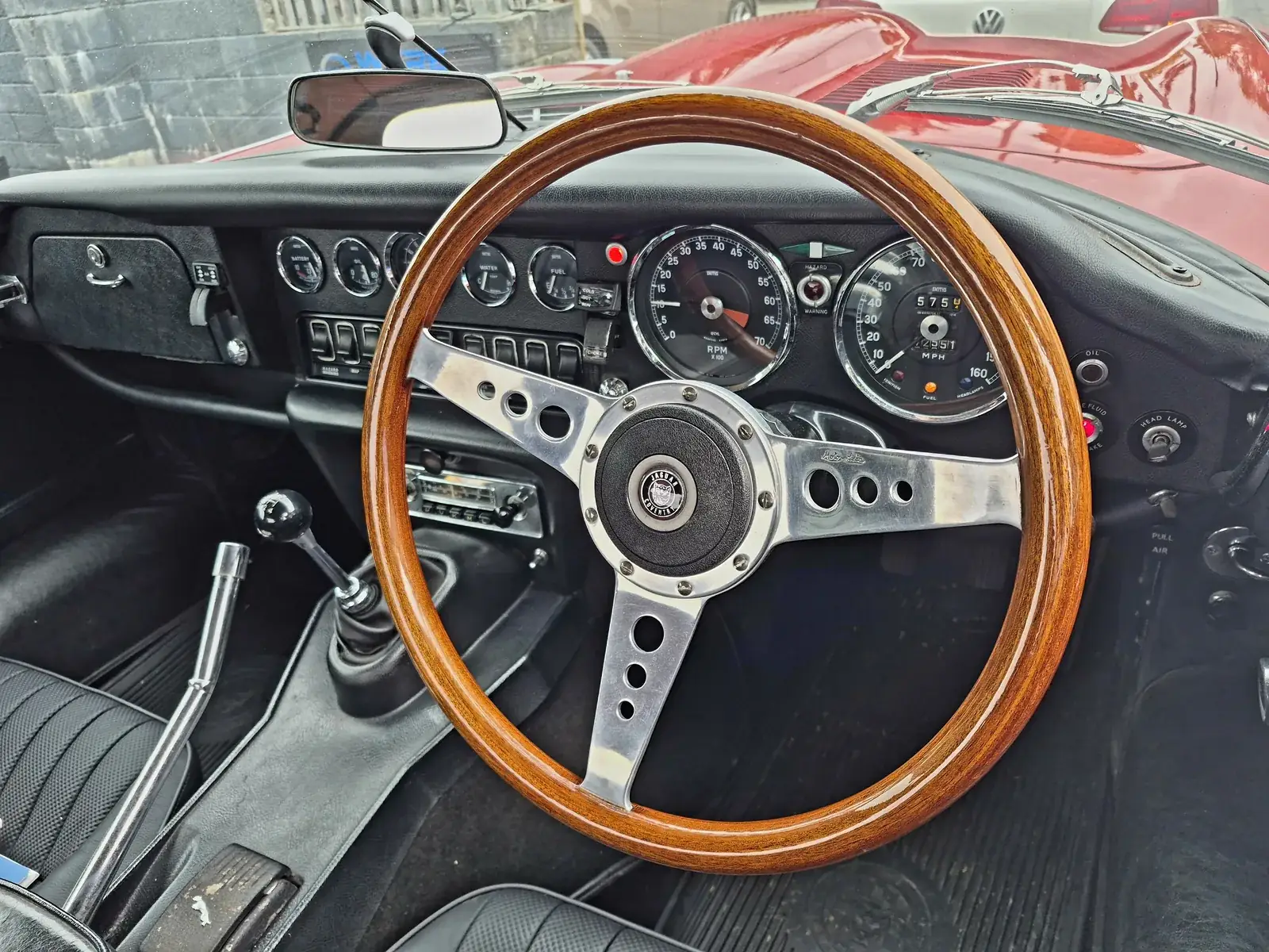 Wood-rimmed steering wheel and Smiths gauges inside a classic Jaguar E-Type, classic car transport Lancashire