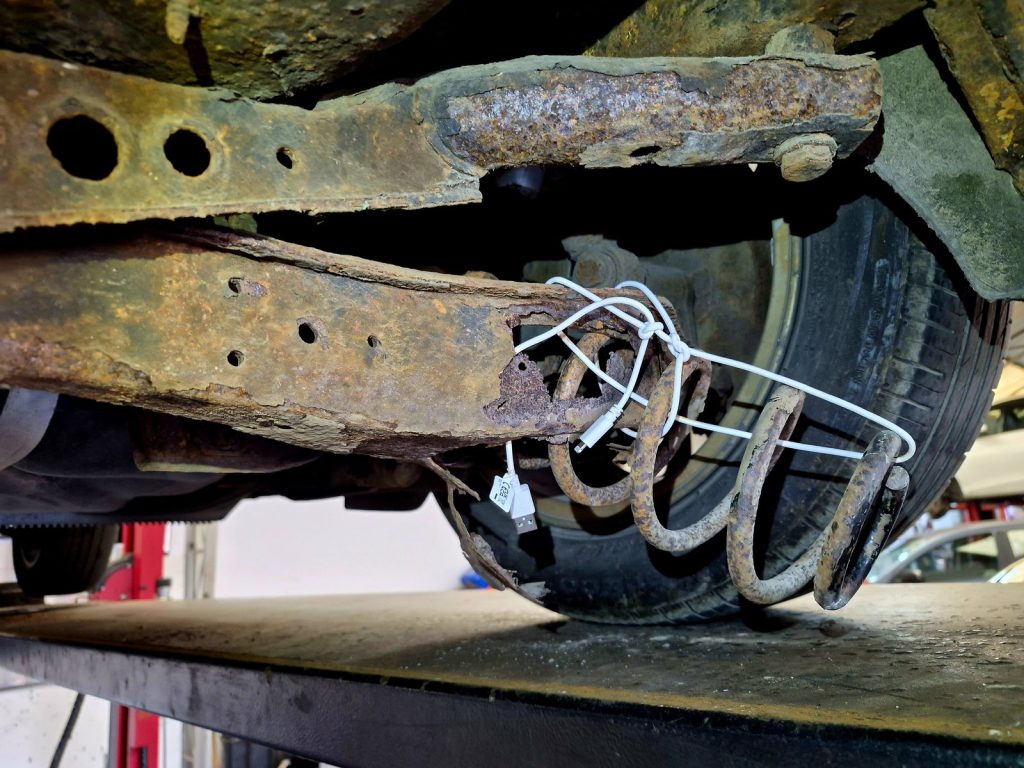 Corroded rear trailing arm found during an MOT test, the coil spring pushed through the bottom of it