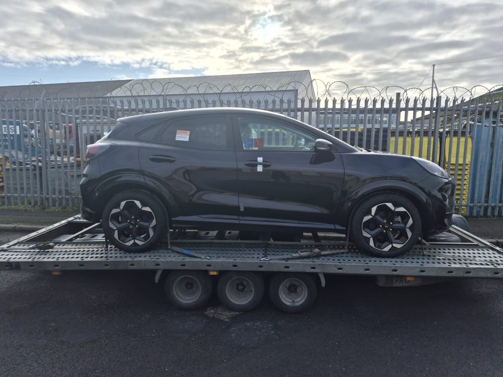 Brand new black Ford Puma Gen-E electric car strapped on a WS Logistics car transporter trailer, ready for electric car transport from Blackpool