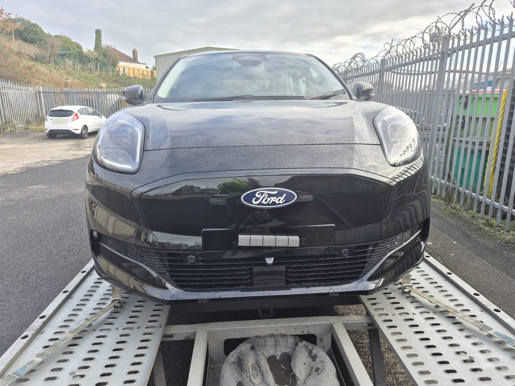 Front of a new black Ford Puma Gen-E electric car secured on a car transporter trailer